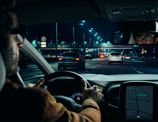 Man die rijdt in het donker met zijn Varilux Roadpilot brillenglazen dashboard en navigatie