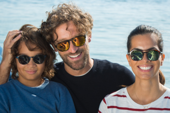 Familie die Essilor-glazen met Xperio Polarised draagt bij de zee